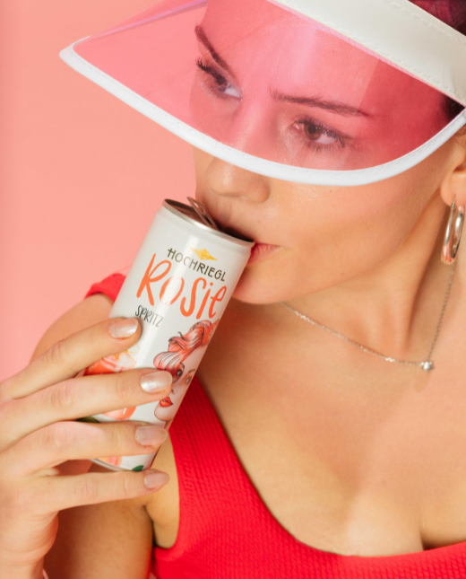 Dame mit rotem Badeanzug und Schildkappe trinkt von einer Rosie Dose