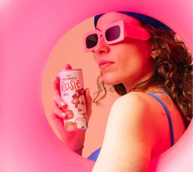 Dame mit Sonnenbrille trägt Hochriegl Sprotz und einen rosa Schwimmreifen