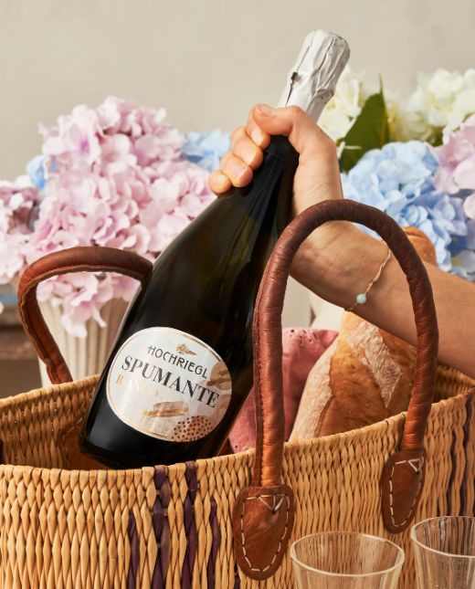 Dame zieht eine Flasche Spumante Bianco aus einer Tasche