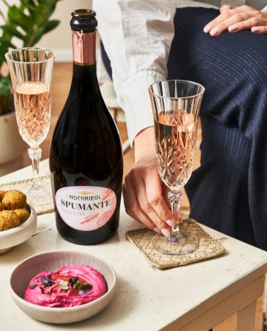 Spumante Rossato mit zwei Gläser, Hummus und Falafel am Tisch mit Dame
