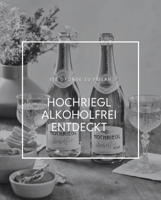 Zwei Flaschen Hochriegl Alkoholfrei stehen am Tisch mit gefüllten Gläsern und Snacks