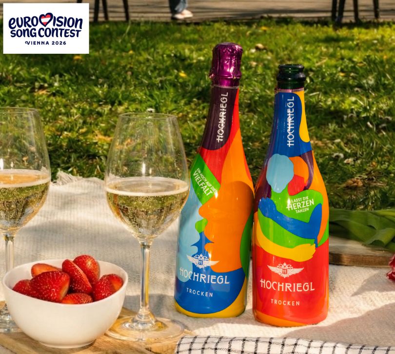 Zwei Flaschen und zwei Gläser stehen auf einer Picknickdecke mit Erdbeeren