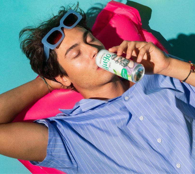 Hann liegt auf Luftmatratze und trinke Hugo Spritz