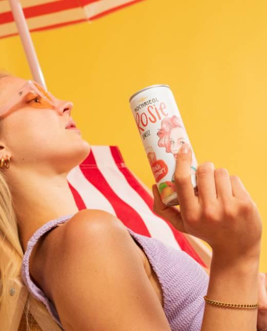 Dame liegt im Liegestuhl und hält eine Dose Rosie Spritz in der Hand
