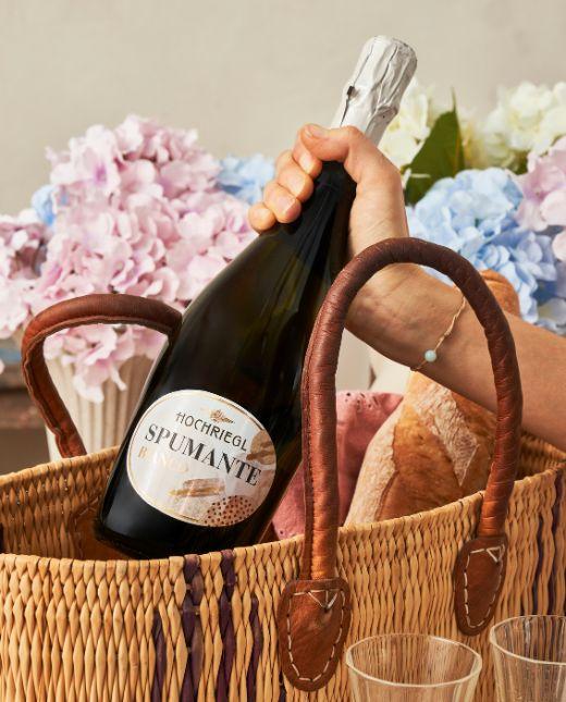 Dame zieht eine Flasche Spumante Bianco aus einer Tasche
